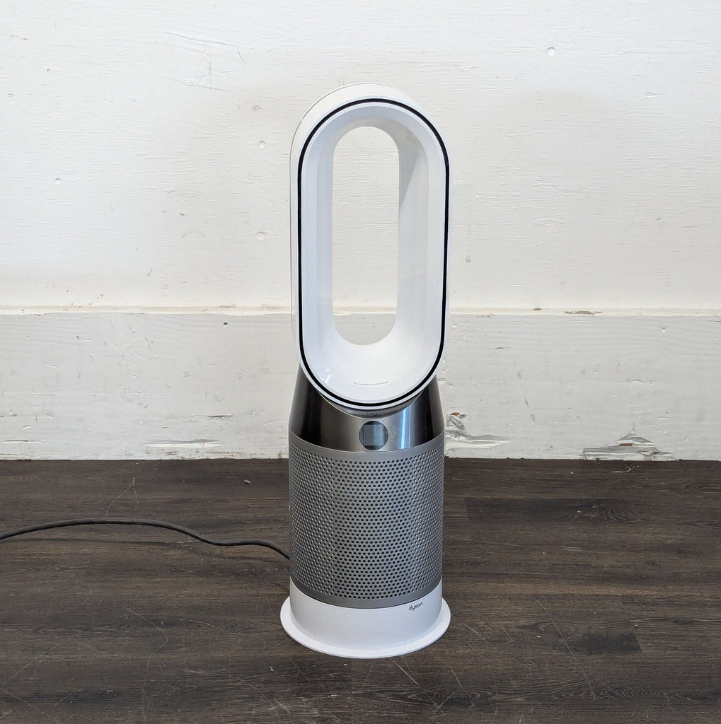 2. Compact Dyson Cooler/Heater fan in white, featuring a tall oval loop and digital controls, on a hardwood floor.  