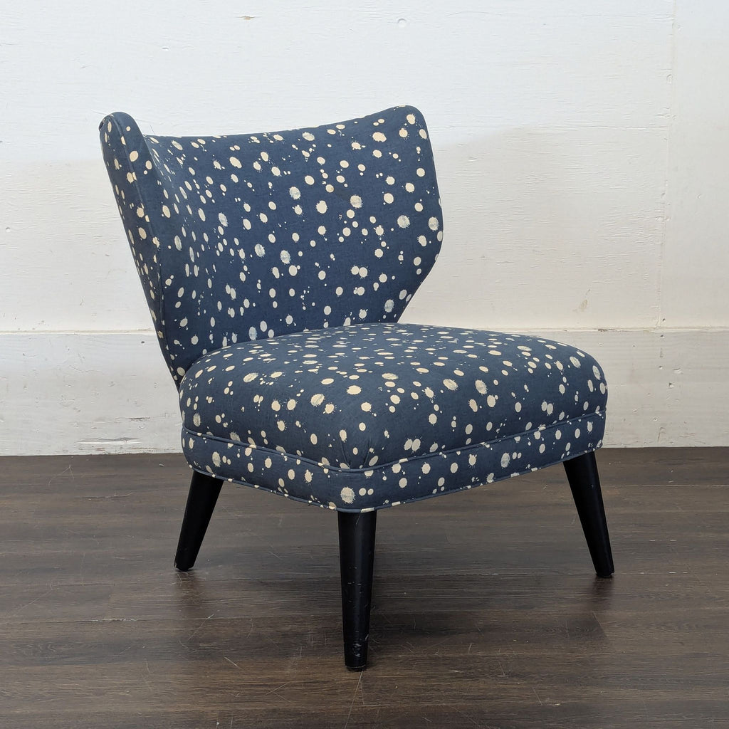Side view of a West Elm + Kate Spade armless lounge chair, navy blue with cream spots and tapered black legs.