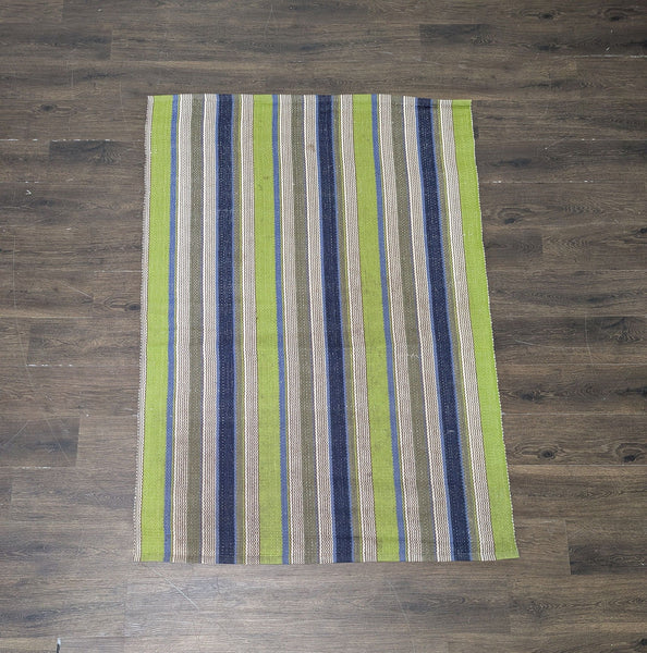 1. A Dash & Albert rug with green, blue, brown, and cream vertical stripes on a dark wood floor.