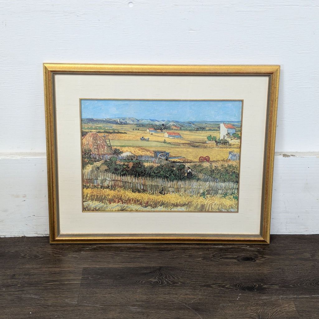 3. Art print showing a panoramic farm landscape in a golden frame, leaning on a wooden floor.
