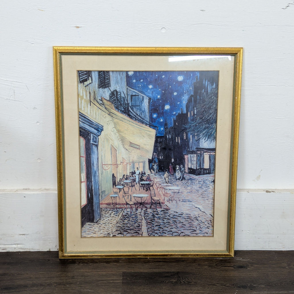 2. Gold-framed art print of a cobblestone street café at night, featuring figures under a vivid starry sky.