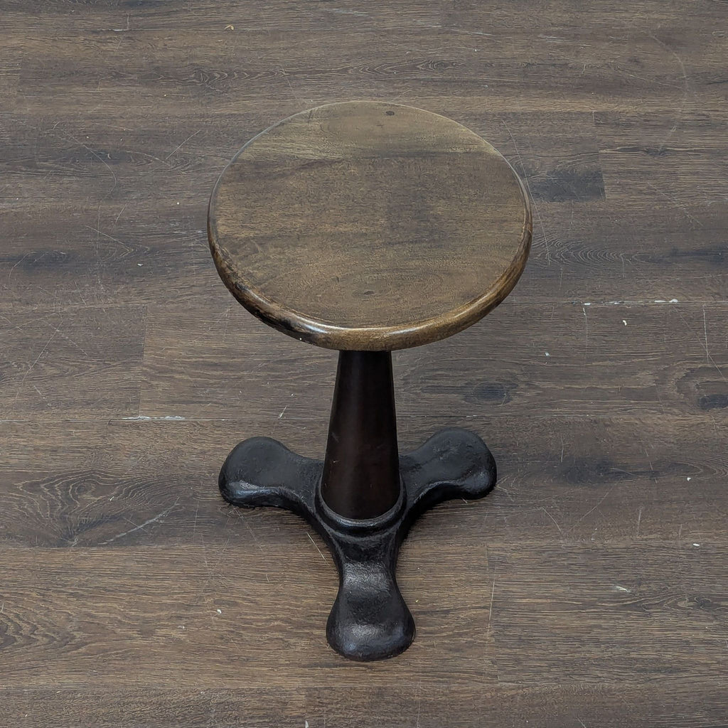 2. A sturdy round wooden-top stool featuring a dark, tapered metal base with wide footed support.