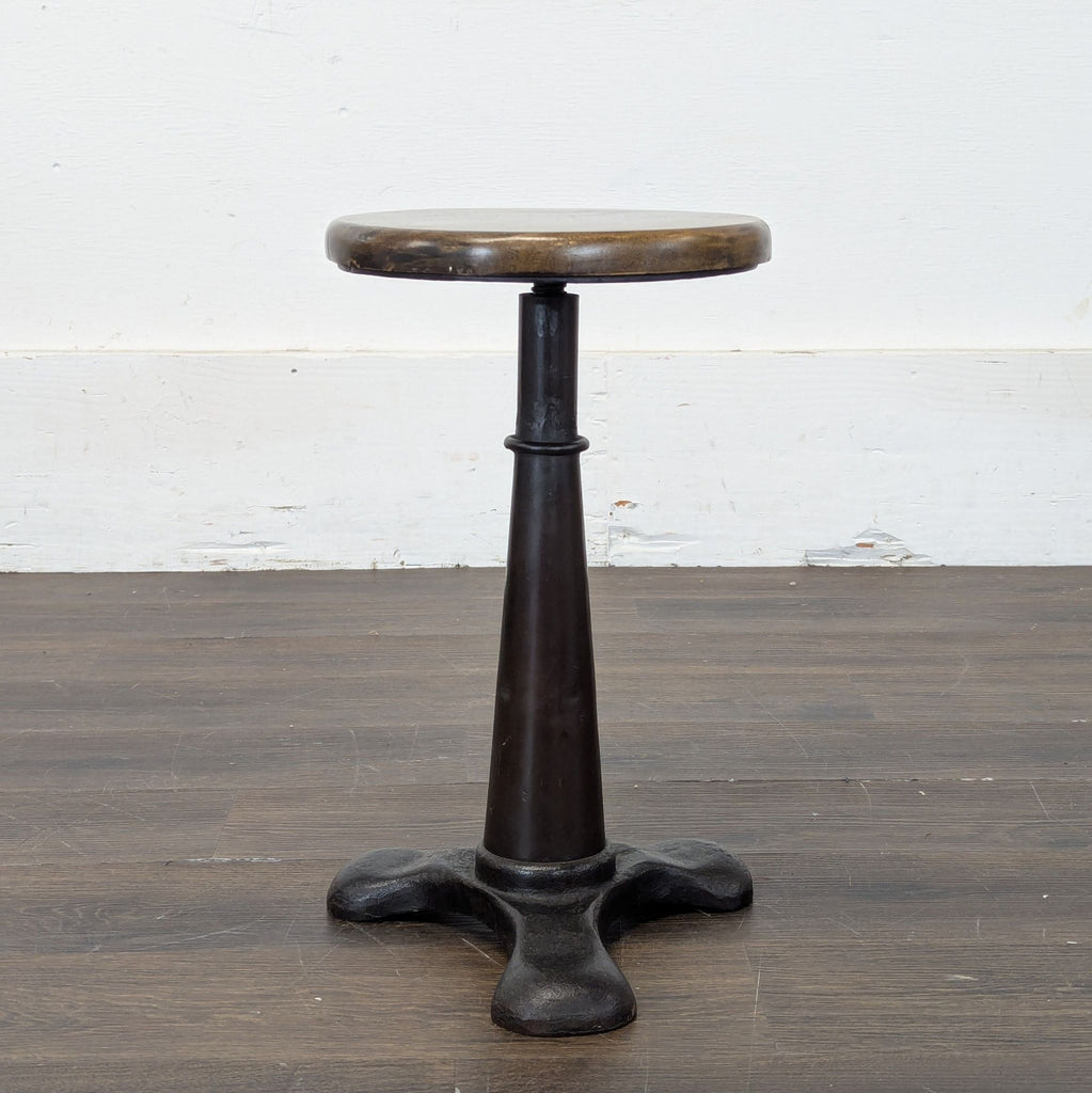 3. Vintage stool with a brown wooden seat and heavy black tripod metal base, perfect for rustic settings.