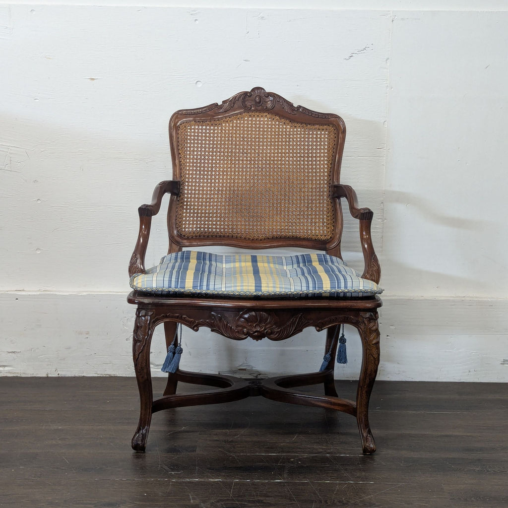 2. Ornate wood dining chair with caned backrest and blue-yellow striped cushion, set against a white wall.  
