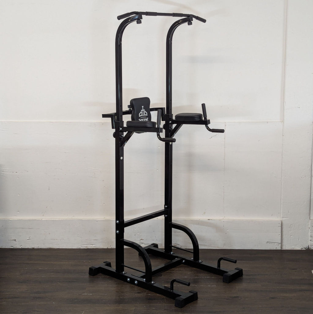 3. Angled view of standalone black power tower gym equipment with handles and pads, on dark wood flooring.