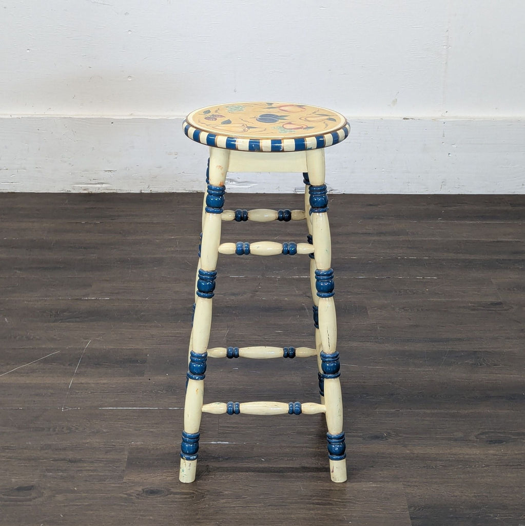 2. Vintage-style wooden stool with blue accents and a decorative round seat, shown on a wood floor.