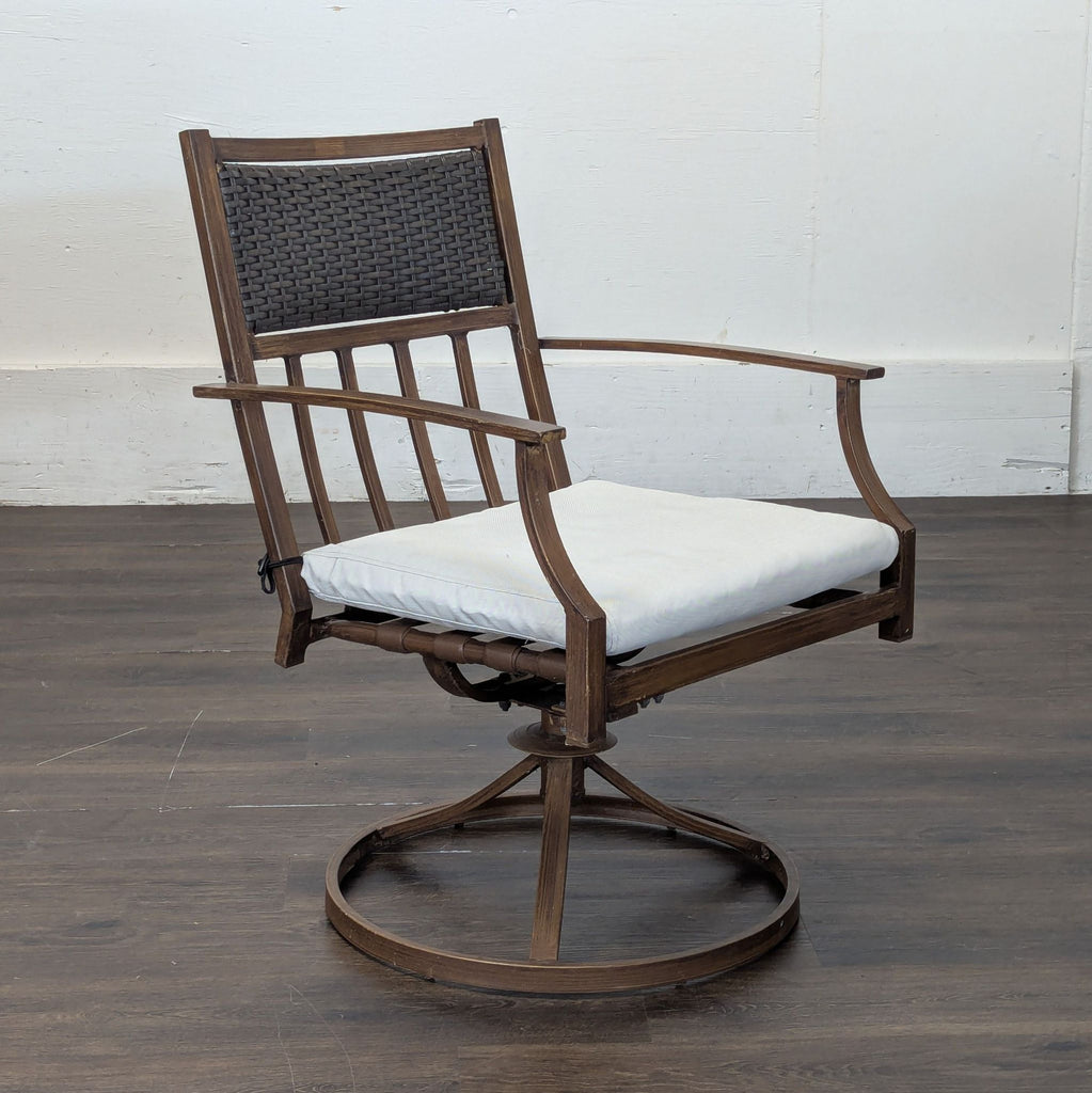 2. Side view of an Orchard chair featuring wood frame, woven backrest, white cushion, and circular metal base.