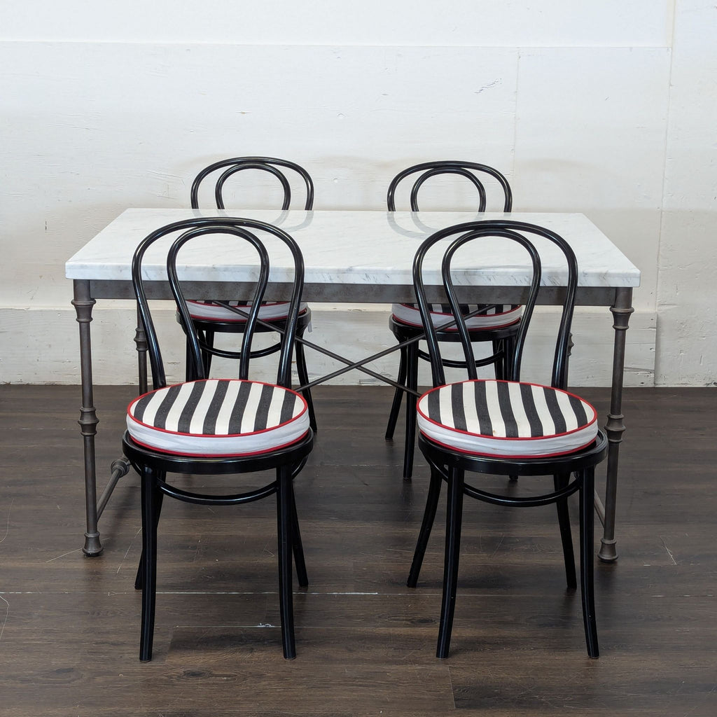 2. Crate and Barrel marble dining set featuring four black chairs with black and white striped seat cushions.