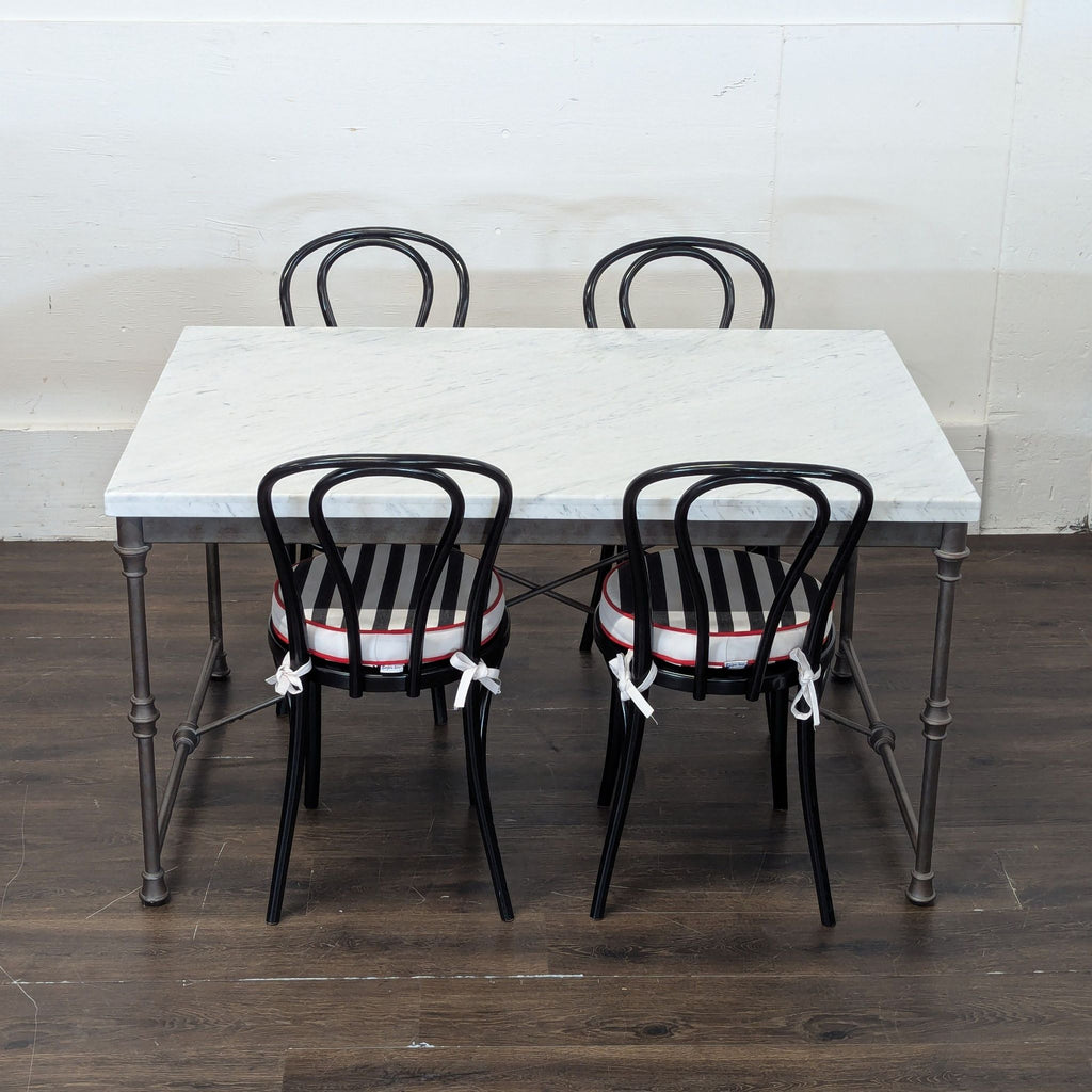 3. Top view of Crate and Barrel marble dining table and four matching black chairs with striped cushions on wood floor.