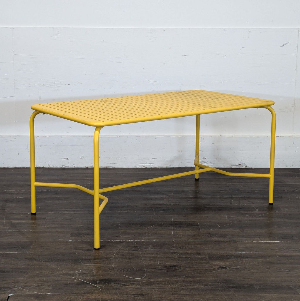 Sleek coral outdoor dining table by Petite Friture, ideal for gatherings; rectangular with modern slatted top.