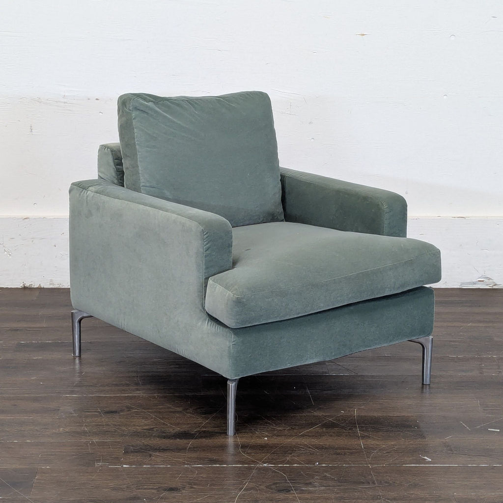 1. Green EQ3 lounge chair with plush cushions and metal legs, shown against a white wall and wood floor.  
