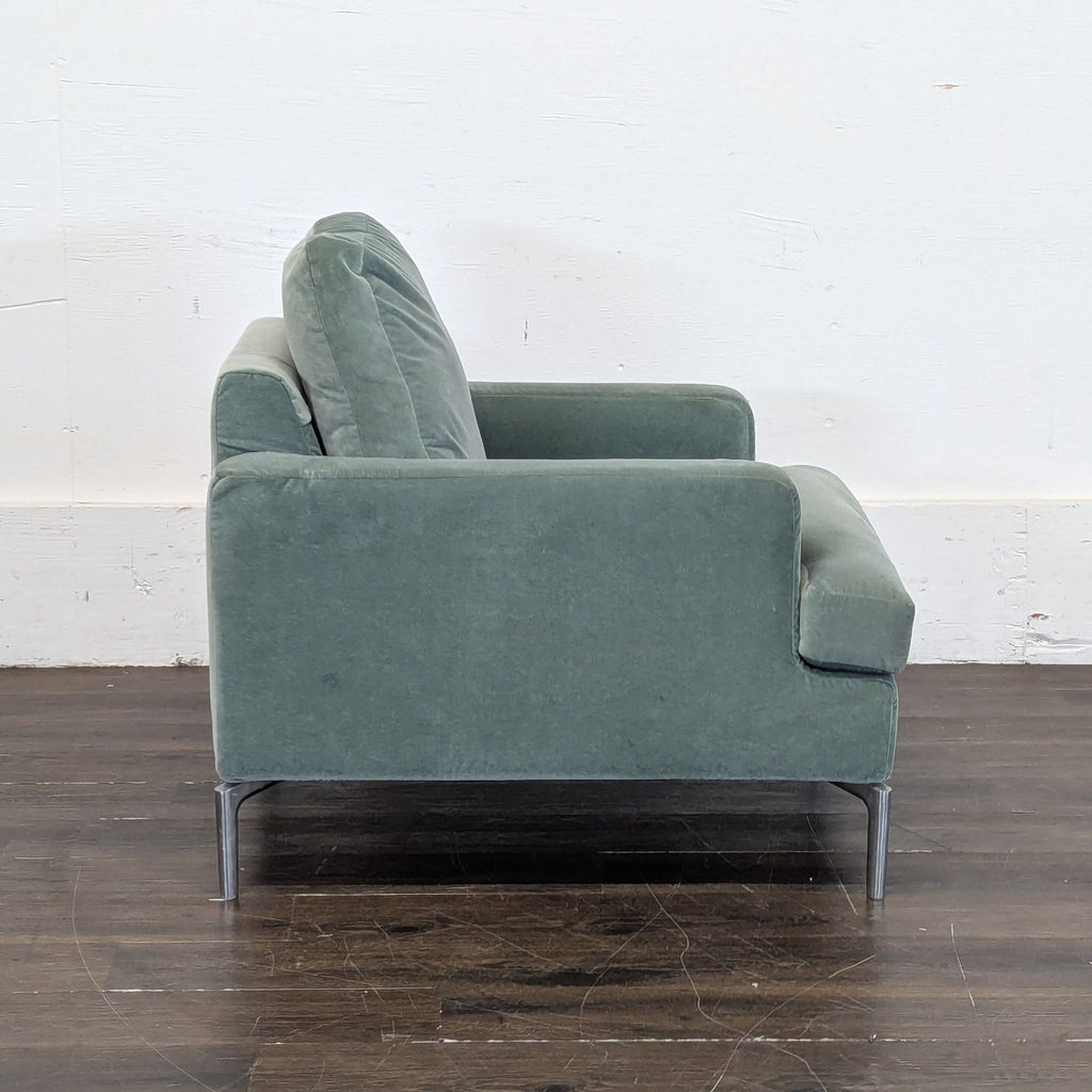 2. Side view of EQ3 brand lounge chair in green fabric with a cushioned back and seat, metal legs visible.