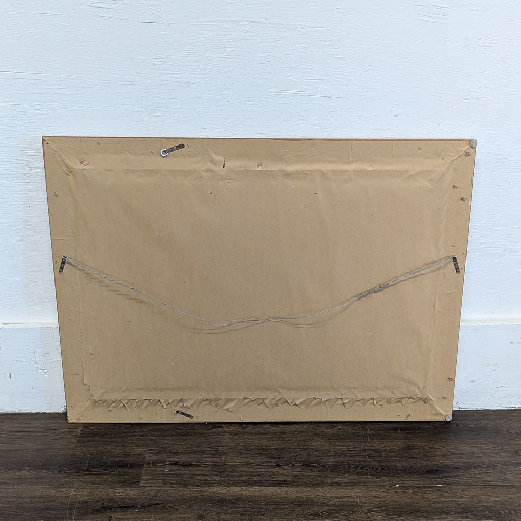 3. Back view of a rectangular mirror, showing brown paper cover and metal wire for wall mounting.