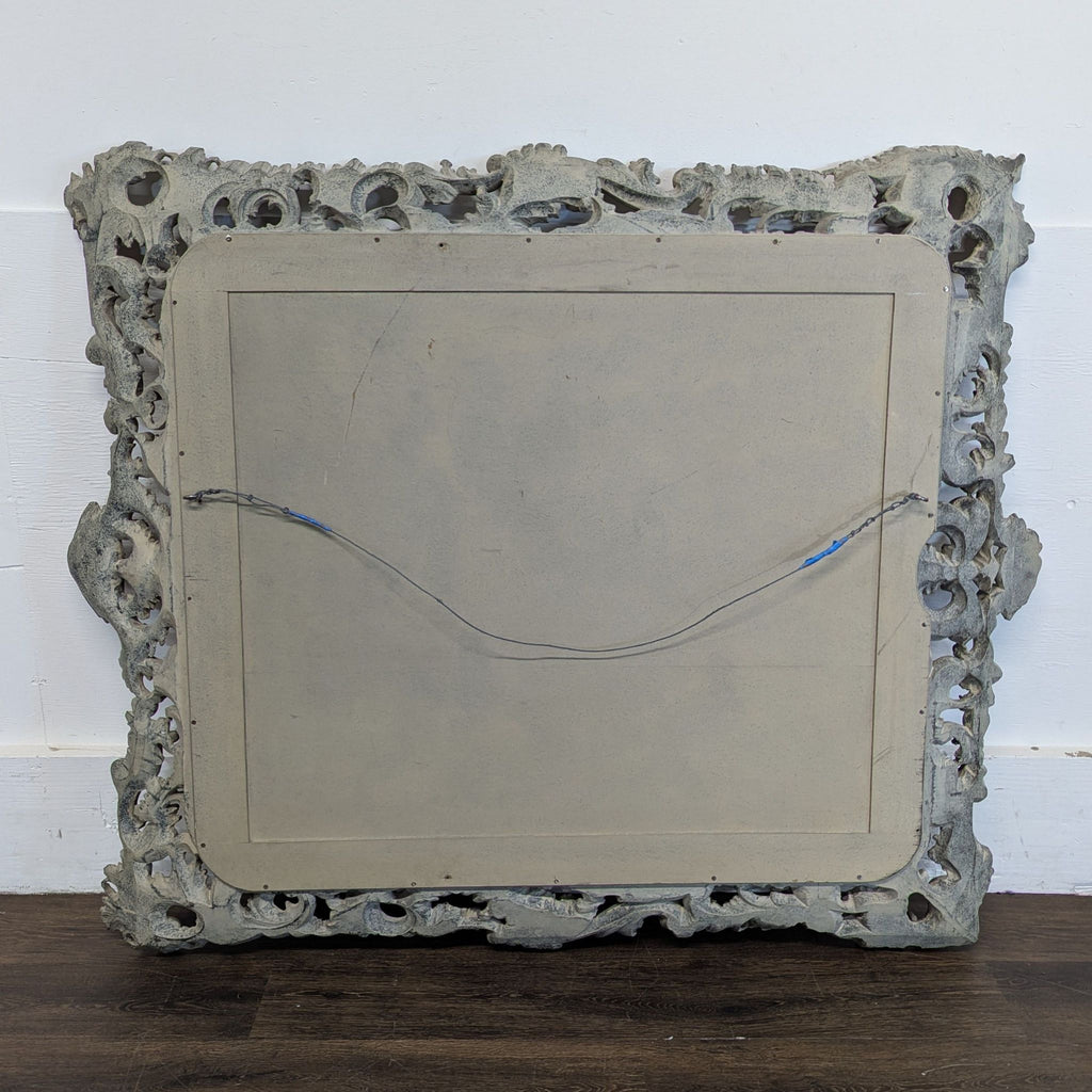 3. Back view of a decorative mirror, showing a detailed frame and attached hanging wire.