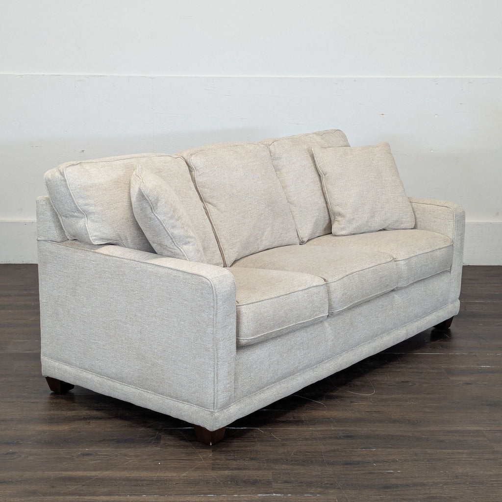 3. Angled view of La-Z-Boy 3-seat sofa in light fabric, highlighting boxy arms and three back pillows on wood legs.