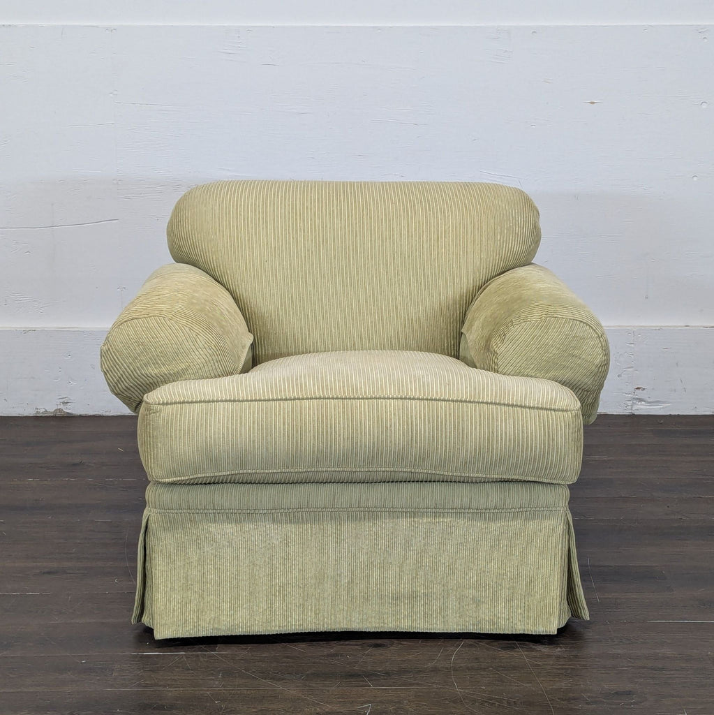 2. Front view of a pale green corduroy lounge chair with plush, rounded arms and skirted base.