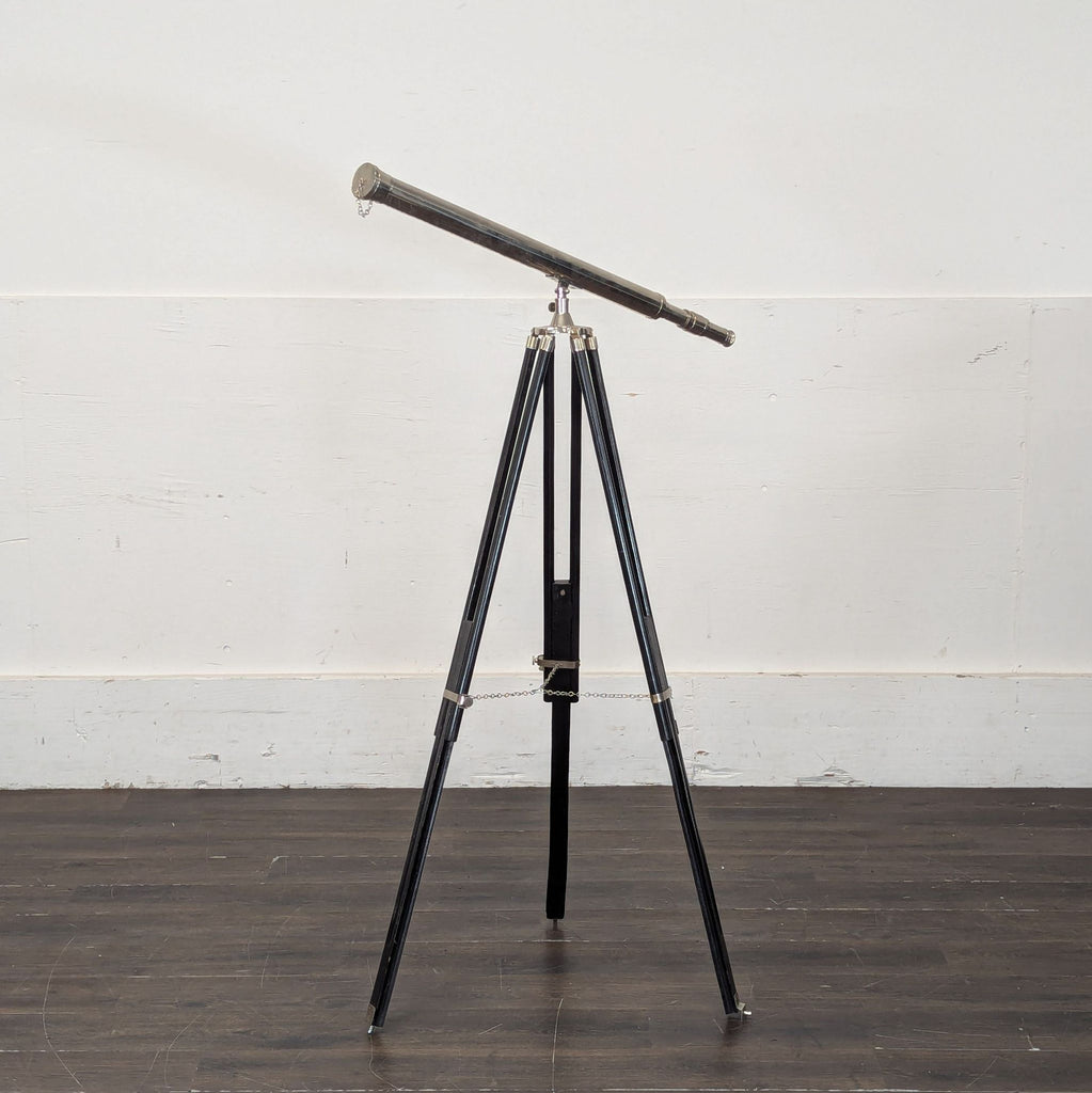 2. A vintage-style metal telescope on a black three-legged stand, displayed in a room with wooden flooring.