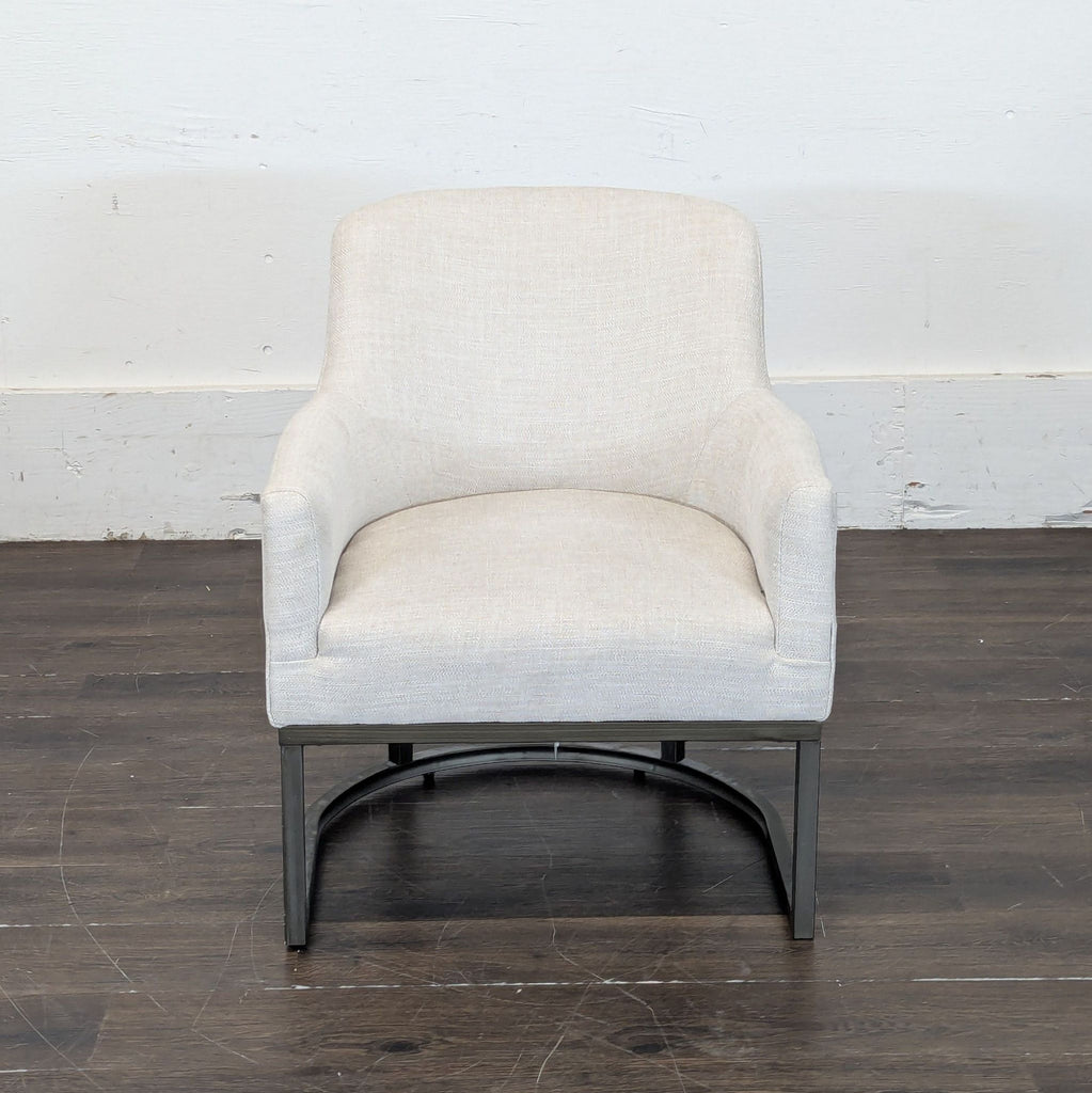 3. Neutral-toned E&E Co. lounge chair featuring soft fabric and dark metal base on a wood floor.