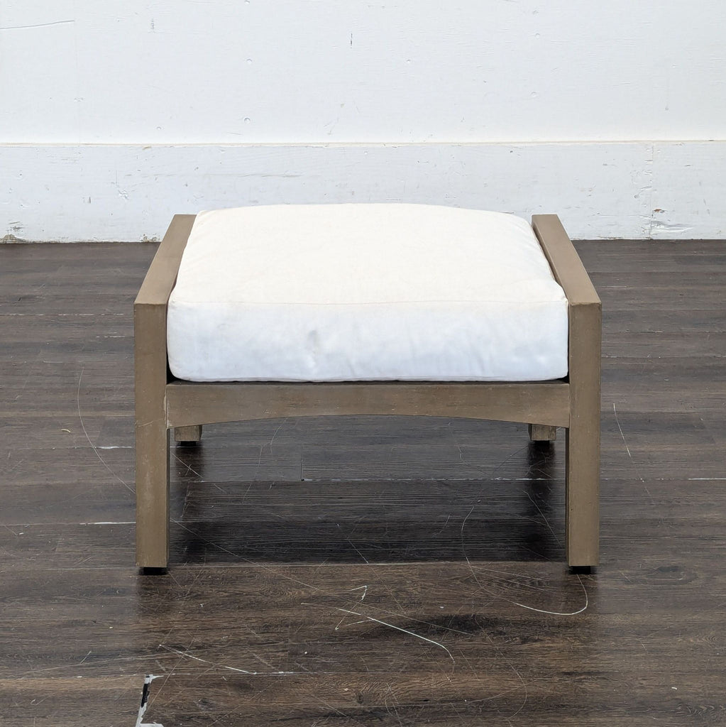 2. Front view of a small square stool featuring a natural wood frame and thick white cushioned seat.  