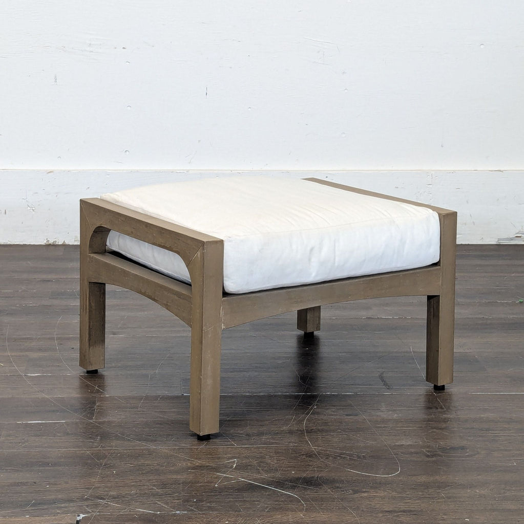 3. Angled view of a modern wooden ottoman with straight legs and a plush white cushion on a hardwood floor.