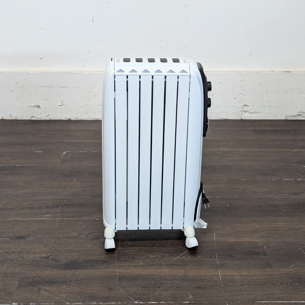 DeLonghi white radiator-style heater on wheels, cord wrapped at the base, shown from a narrow end view.