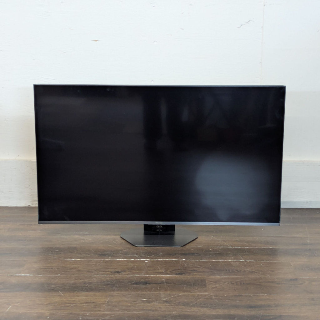 1. Modern flat-screen TV with slim bezels displayed on a wooden TV stand in a living room.