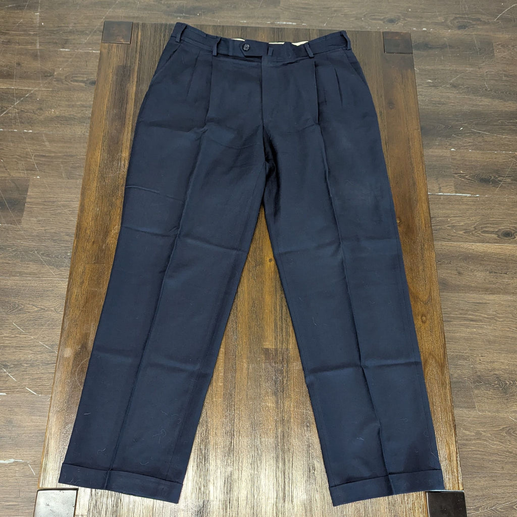 1. Front view of men's navy dress pants with pleated front and belt loops, laid flat on a wooden surface.