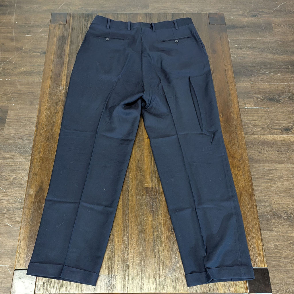 2. Rear view of men’s navy dress pants showing buttoned back pockets and classic tailoring on a wooden table.