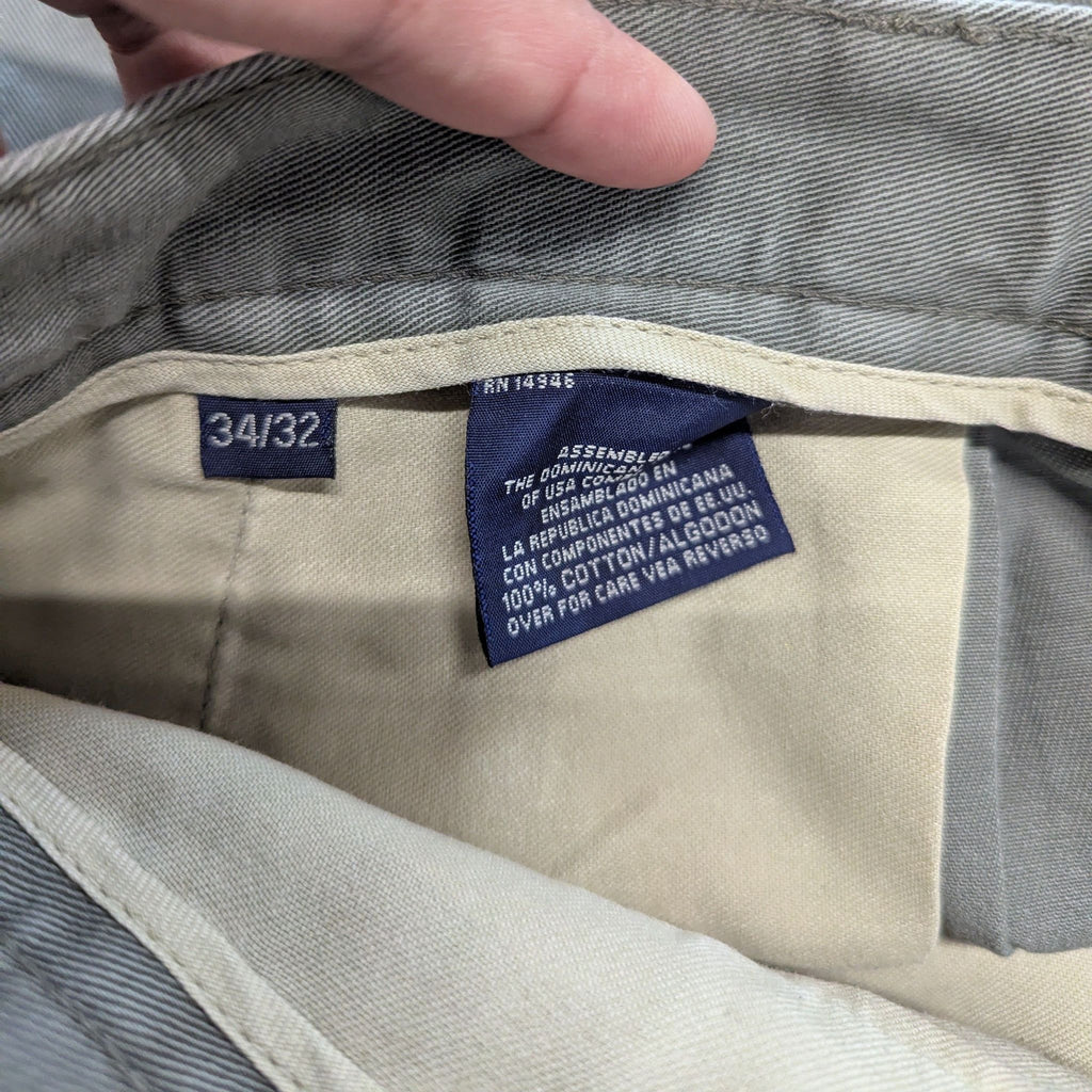 Close-up of inside waistband of men's khaki pants showing size tag (34/32) and care labels.