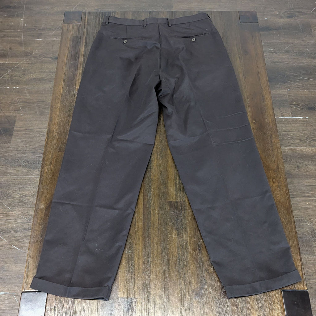 2. Rear view of men's black dress pants showing back pockets, displayed on a wooden table.