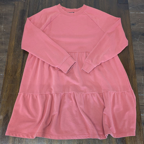 1. Pink Monki women’s long sleeve dress with tiered skirt, shown laid flat on wooden surface, viewed from the front.