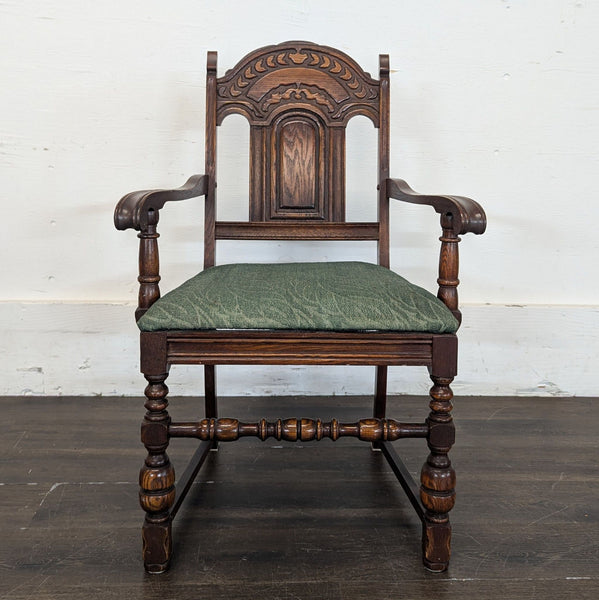 1. Ornate wooden dining chair with carved backrest, curved arms, and a green upholstered seat, front view.