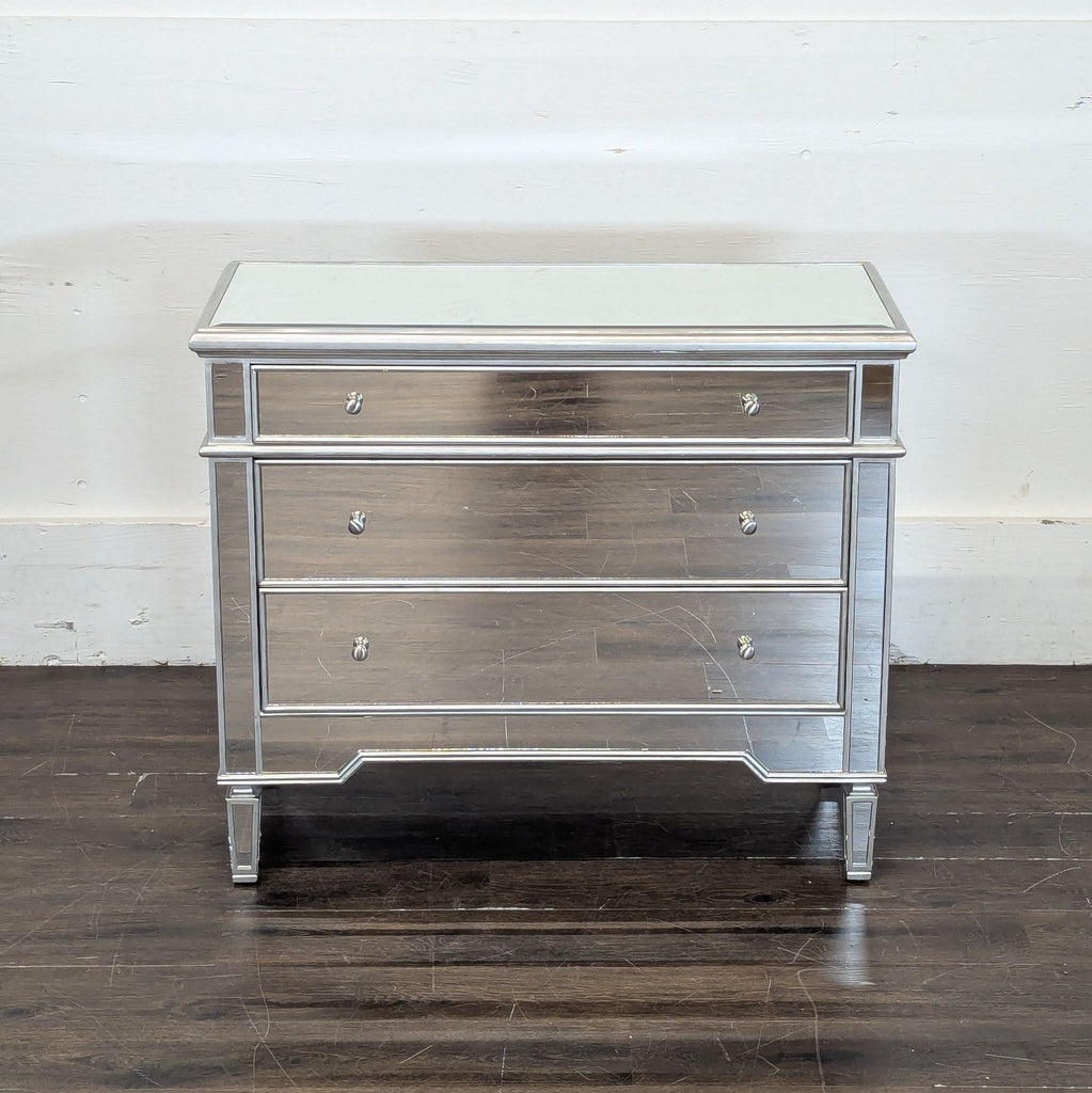 2. Mirrored end table by Worlds Away featuring three drawers, reflective finish, and metal detailing, against white wall.