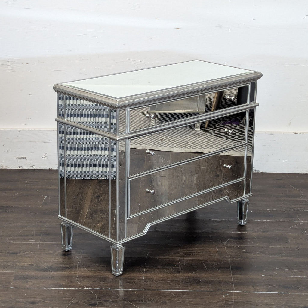 3. Angled view of Worlds Away end table showing mirrored surfaces, silver edges, and three-drawer design on dark floor.