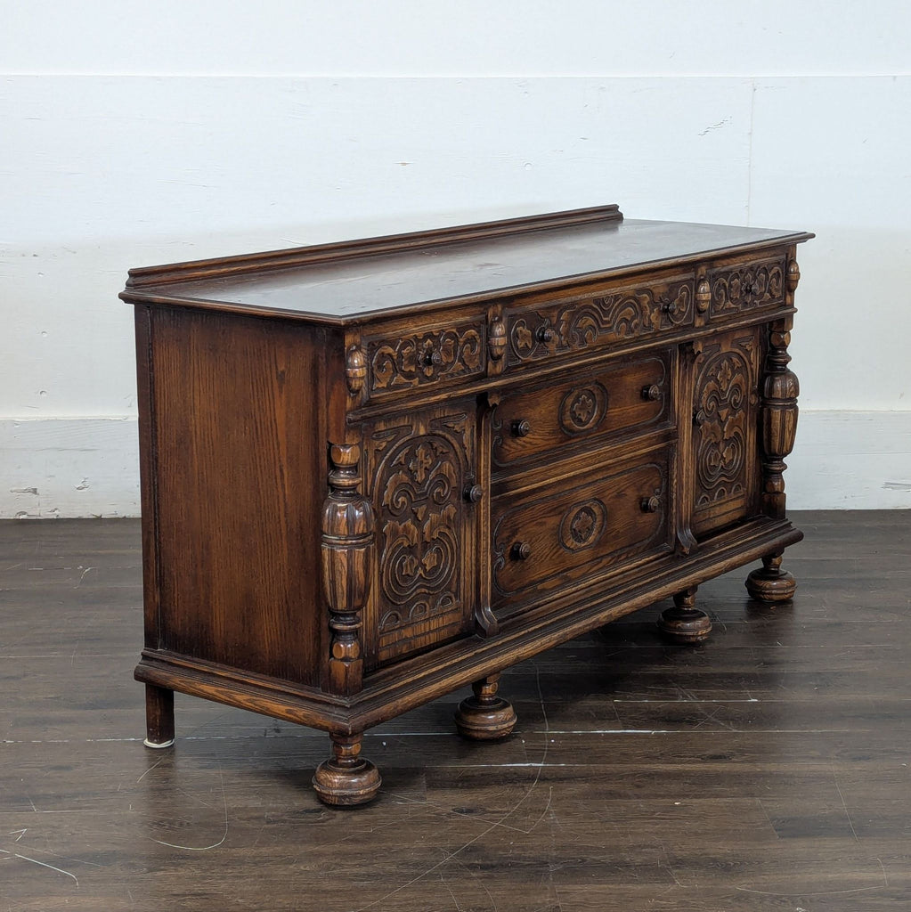 Vintage sideboard with intricate front panel carvings, three drawers, and two large storage compartments.