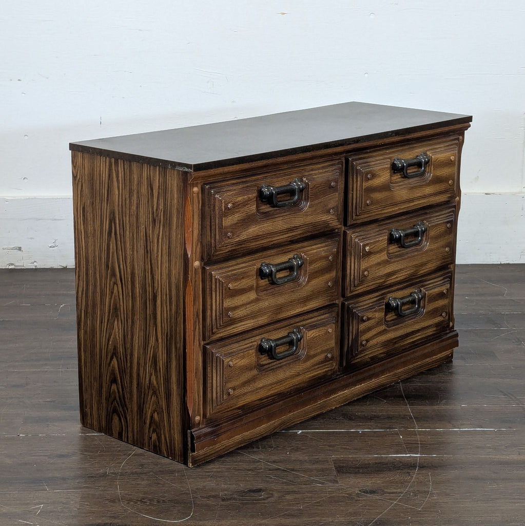 2. Angled side view of a wooden dresser with six drawers and metal handles, placed on a wooden floor.