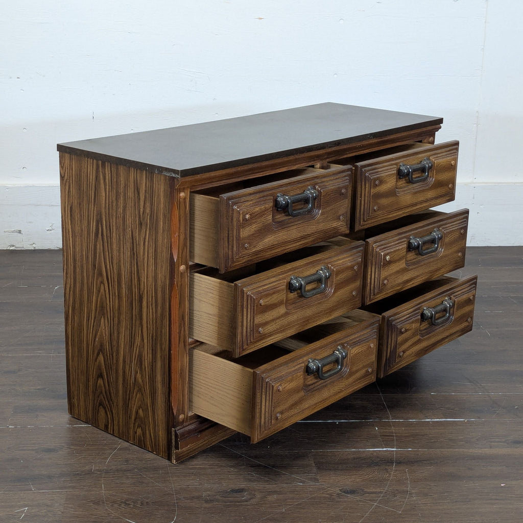 3. Three-quarter view of a wooden dresser with six drawers, with all drawers partially open, showing storage.