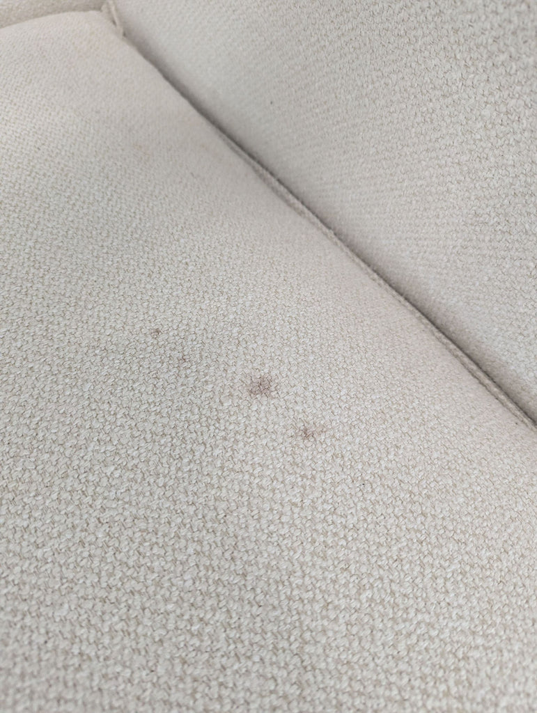 2. Detail of light beige Crate & Barrel 3-seat sofa cushion showing small visible stains on the fabric.