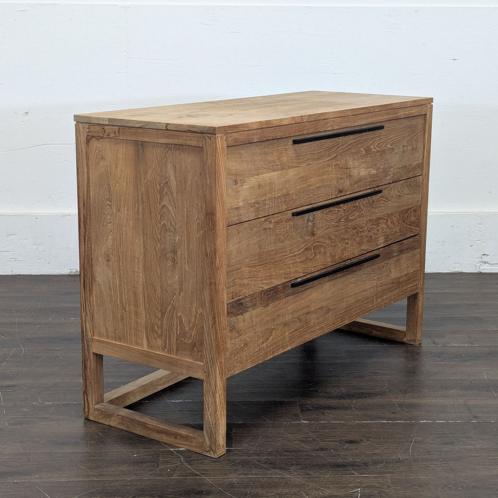 3. Side angle of a Crate and Barrel wooden dresser, showcasing three black-handled drawers and modern design.