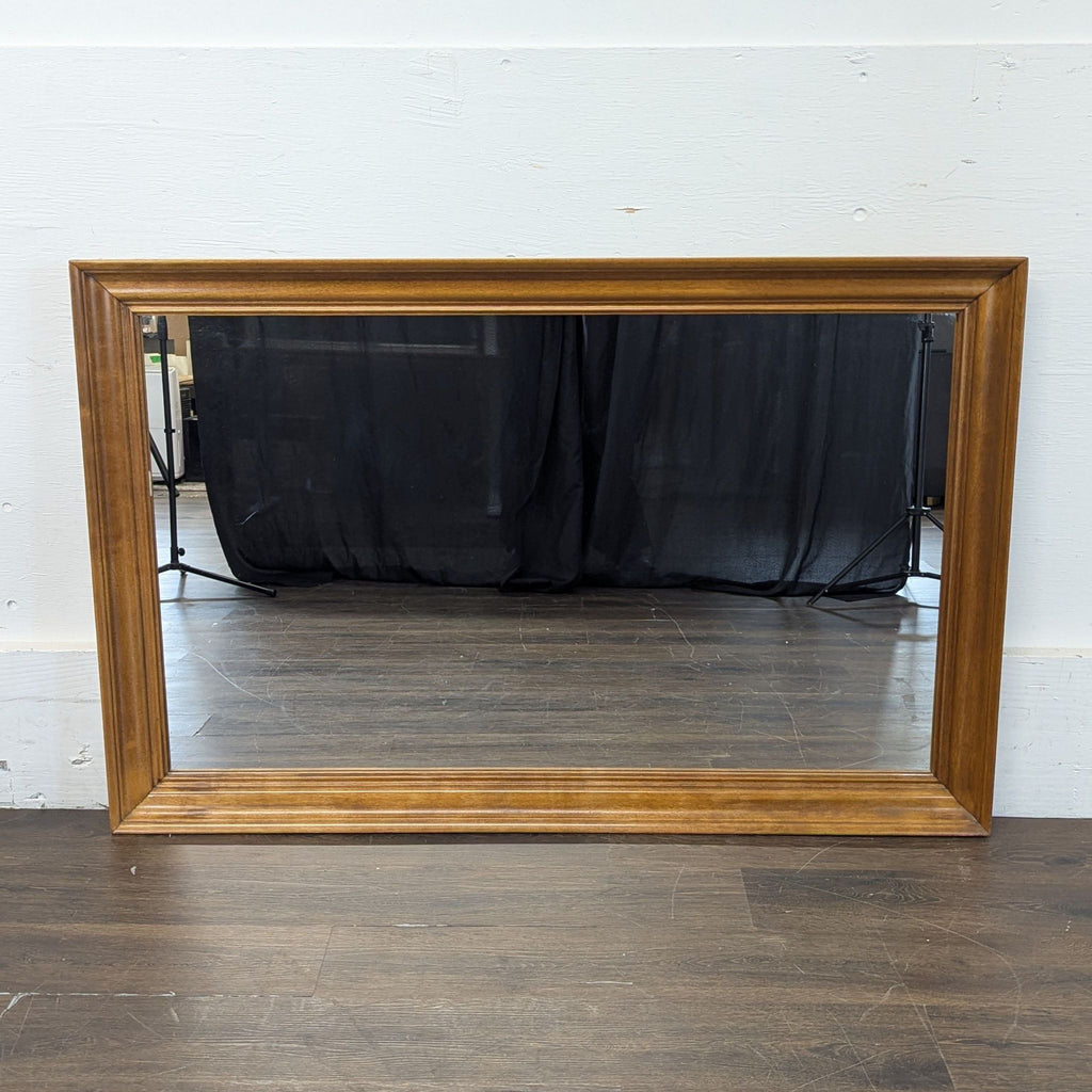 Freestanding floor mirror with minimalist design, placed against a neutral-colored wall.