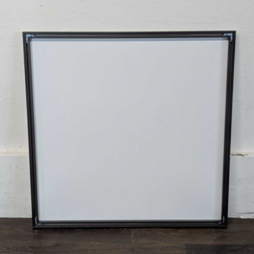 3. Back view of a Pottery Barn square mirror, showing its sturdy black frame construction against a white wall.