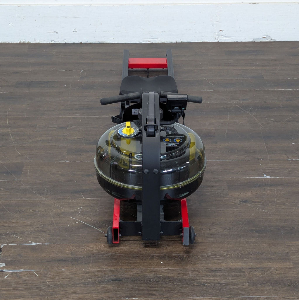 2. Front view of a First Degree Fitness water rowing machine showing seat, handles, and clear water tank on wooden flooring.