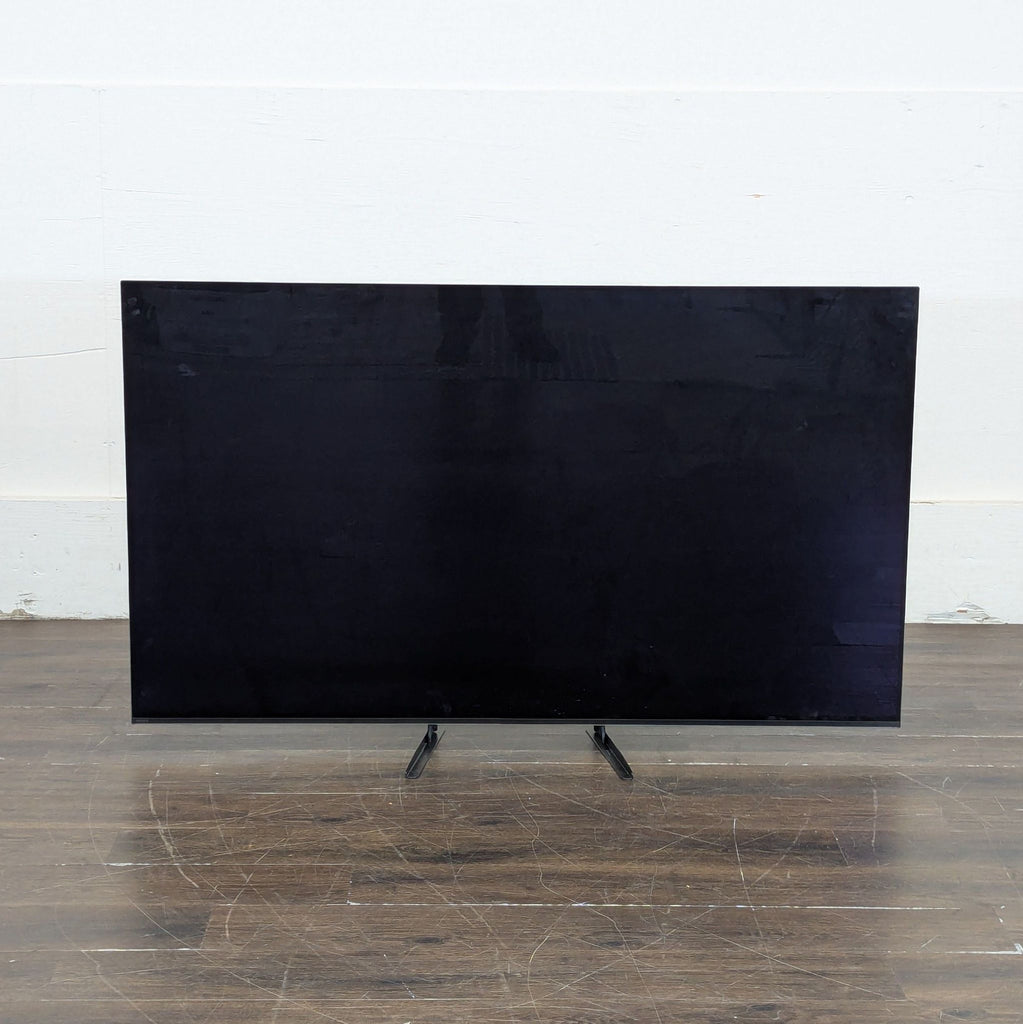 3. Sony TV on a stand with the screen off, placed against a light-colored wall on a wooden floor.