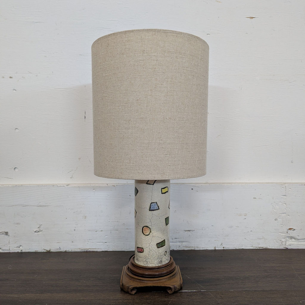 1. Table lamp with beige fabric shade, ceramic base with colorful geometric shapes, and wooden stand.