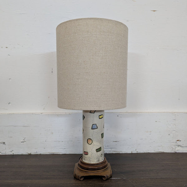 1. Table lamp with beige fabric shade, ceramic base with colorful geometric shapes, and wooden stand.
