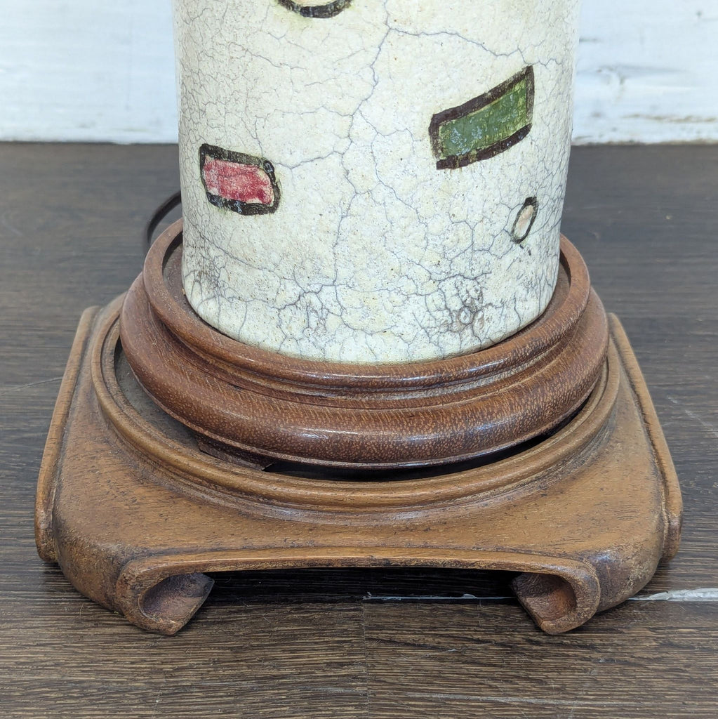 3. Detailed view of the lamp’s carved wooden stand supporting a ceramic base with colorful abstract patterns.