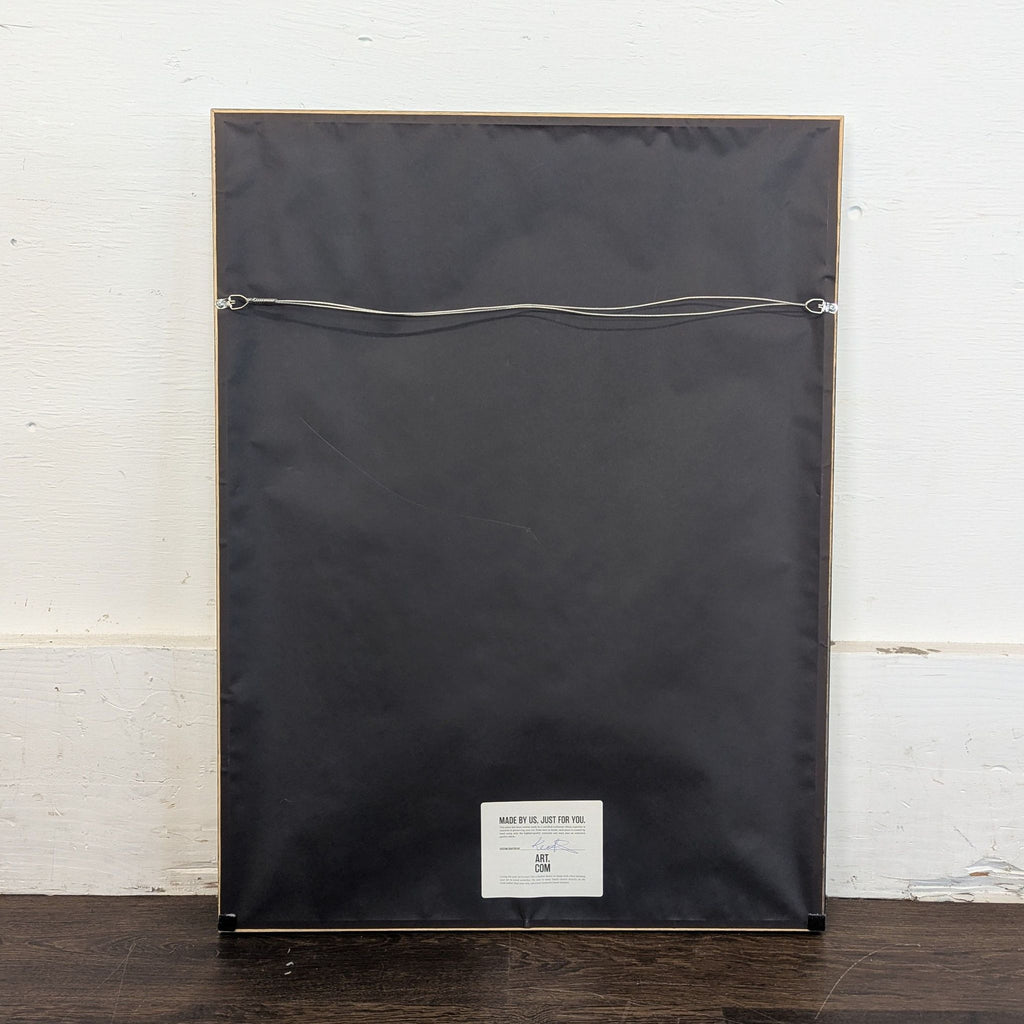2. Back view of the framed art print, showing a plain black cover with a hanging wire.