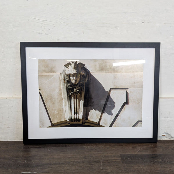 1. Framed art print featuring a detailed photograph of an ornate stone face sculpture on a building facade.