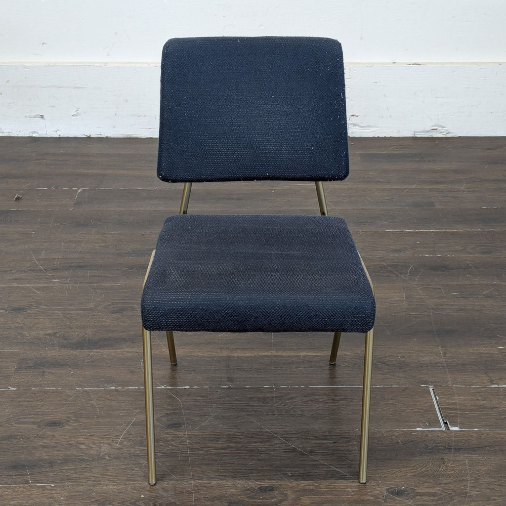 3. Navy upholstered West Elm dining chair with gold legs, viewed from above on a wooden floor.