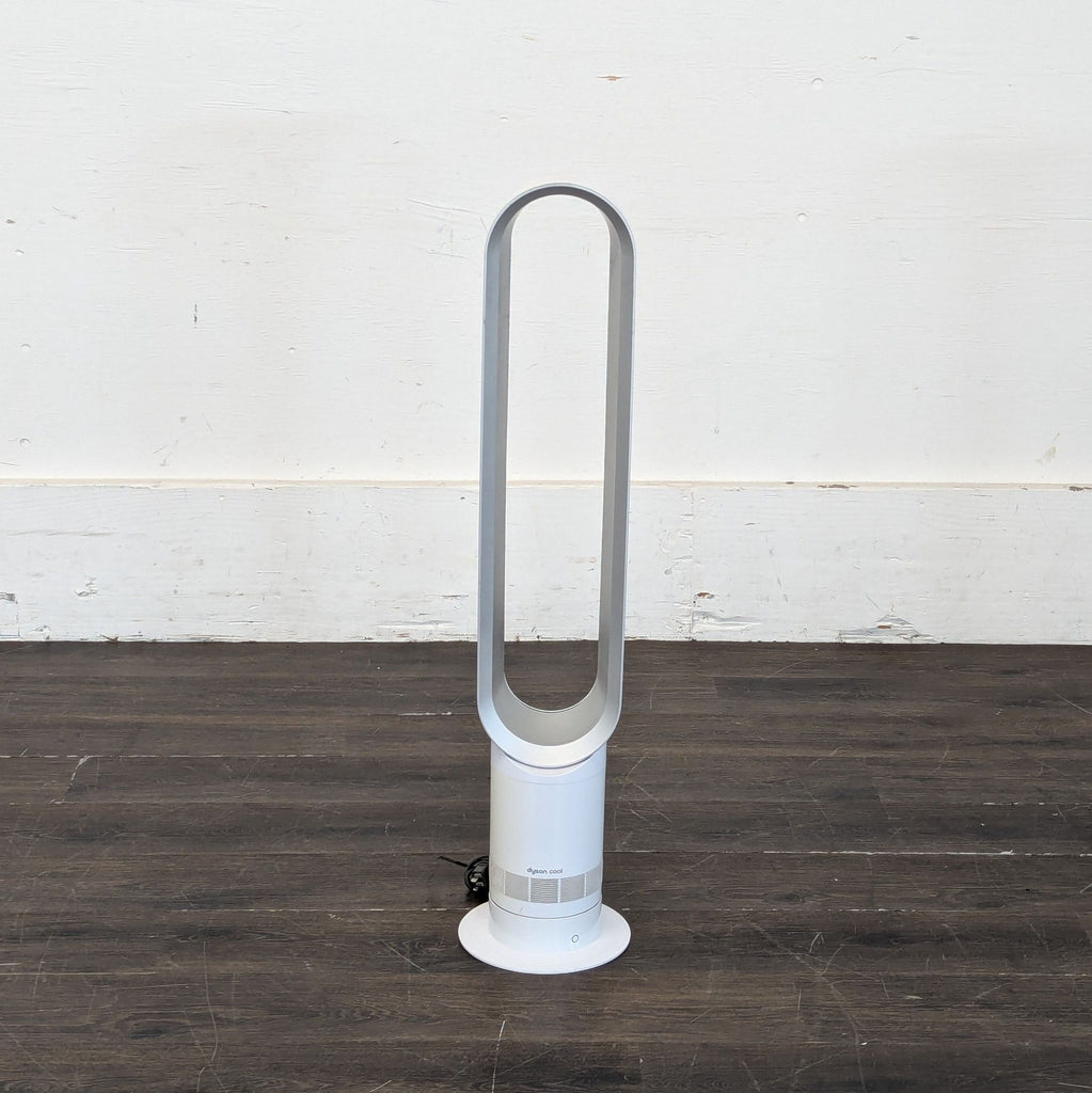 1. Front view of a Dyson bladeless fan in white, standing on a dark wood floor against a plain wall.